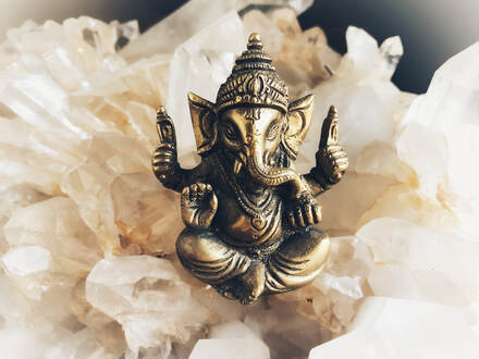  A bronze statue of Lord Ganesha, the Hindu deity with an elephant head, placed on a large quartz crystal
