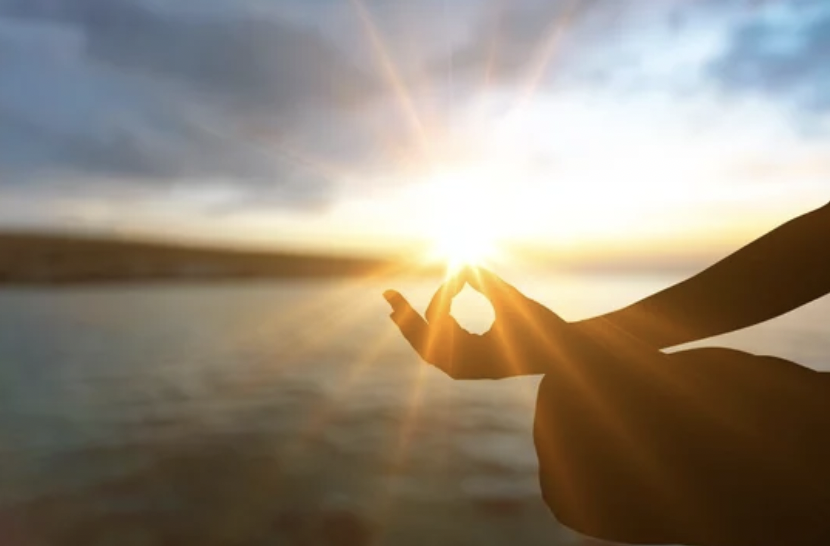 Meditator embracing the rising sun's energy, representing inner harmony and connection.